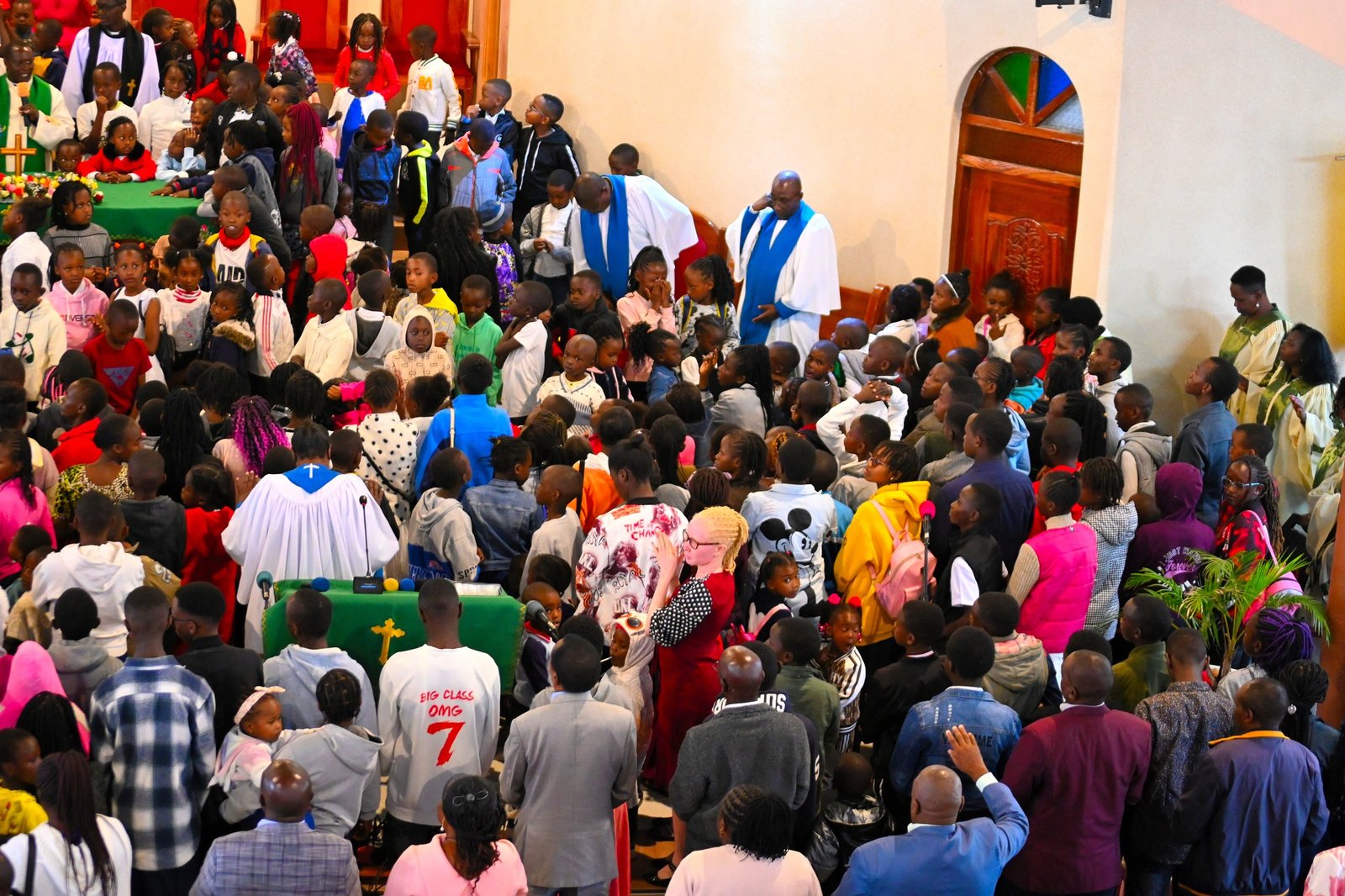 Congregation raising hands in worship inside a sunlit church
